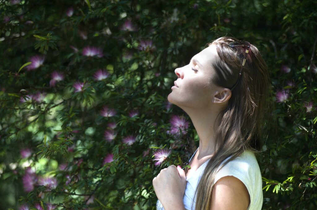 Lady gazing into the sunshine holding a flower