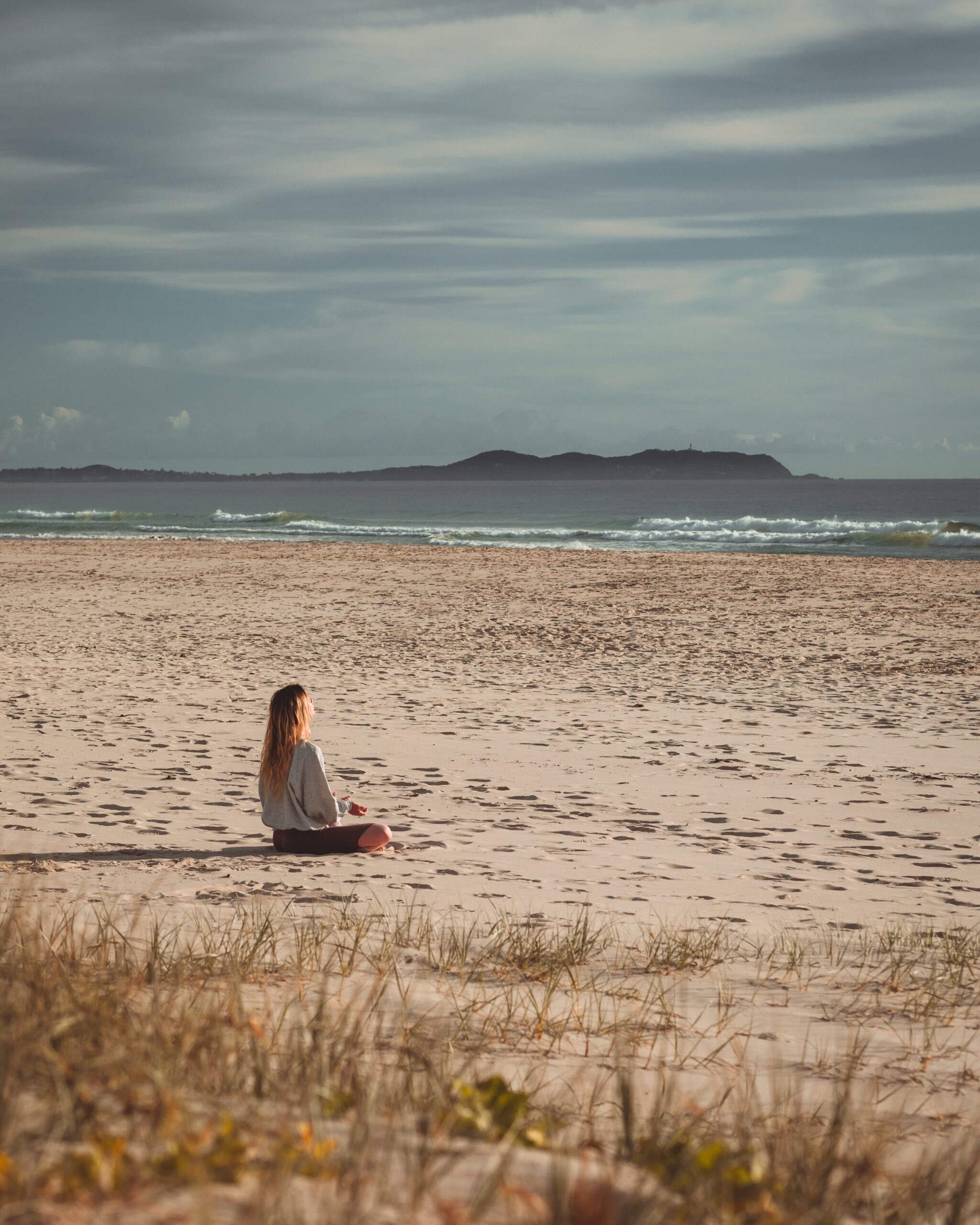 Lady boosting mood by sitting on beach meditating
